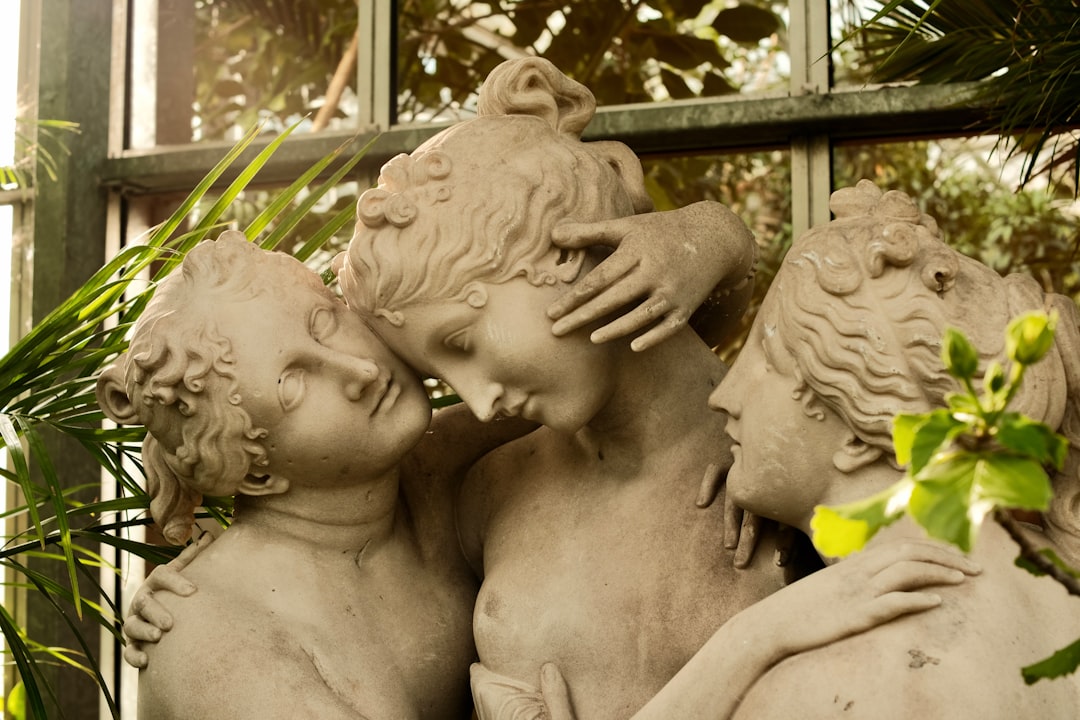 a-statue-of-three-cherubs-in-front-of-a-window-aw5hr8tjafo